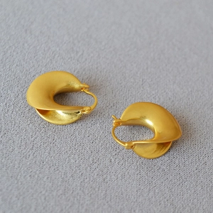 Macro view of French vintage matte gold geometric twisted earrings on knit fabric