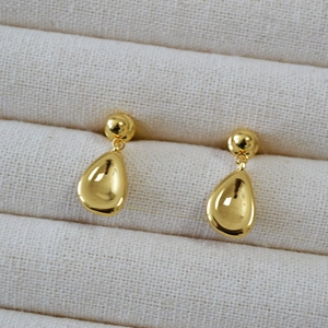 Elegant gold teardrop earrings with a polished mirror finish on a jewelry box liner