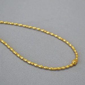 Macro shot of matte gold-plated beads and linkage texture on a minimalist beaded necklace