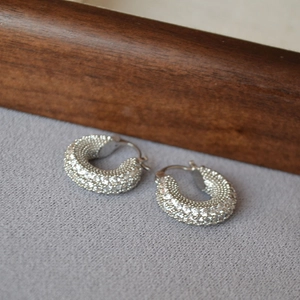 Macro shot of silver chunky hoop earrings with pave cubic zirconia and clasp detail