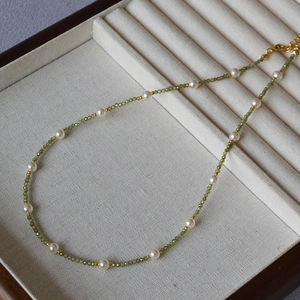 Detail of green beaded necklace with white pearls and gold spacers on velvet