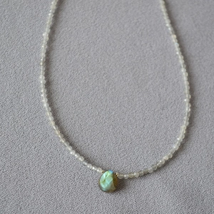 Detailed close-up of beaded necklace with labradorite teardrop pendant showing blue sheen