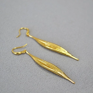 Macro shot of long gold leaf earrings featuring delicate stripes and white rhinestones