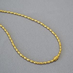 Minimalist gold plated baroque bead necklace featuring an irregular charm on grey felt