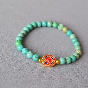 Detailed shot of turquoise bead bracelet with enameled ruyi cloud pendant and gold accents