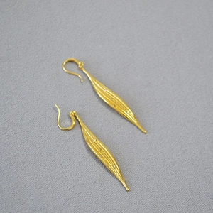 Detailed view of long gold leaf earrings with textured finish and zircon accents