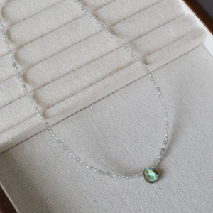 Detail of beaded necklace featuring faceted grey stones and a teardrop labradorite pendant