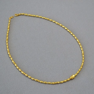 Macro shot of gold-plated brass beads and oval pearl accents on a necklace strand