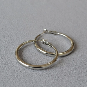 Close-up of polished silver oversized hoop earrings with smooth metallic finish