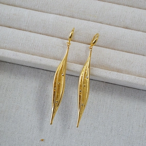 Detail of gold zircon leaf earrings featuring long streamlined design and textured finish