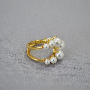 Vista macro di anello in ottone placcato oro con perle su tessuto grigio