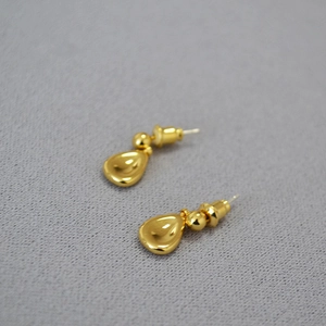 Detail of gold-plated brass teardrop earrings with a polished spherical stud design