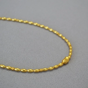 Detailed close-up of matte gold olive beads and cylindrical clasp on a vintage necklace