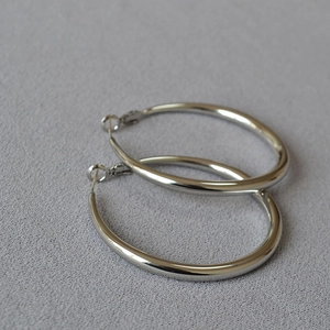 Detailed close-up of polished silver hoop earrings with secure pin closure mechanism