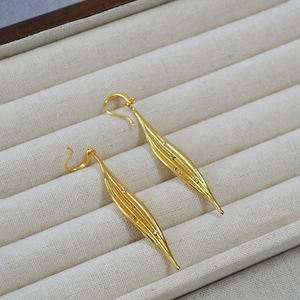 Elegant gold-tone long drop leaf earrings with sparkling zircon crystals on beige velvet