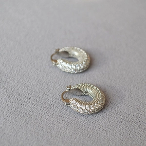 Detailed close-up of chunky silver hoop earrings featuring multiple rows of pavé crystals