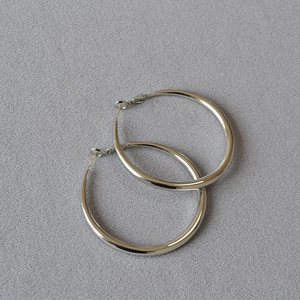 Close-up of classic silver-tone hoop earrings with polished mirror finish on gray texture