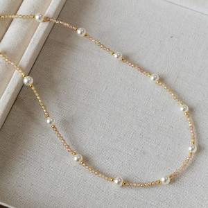Detailed shot of beaded necklace with orange crystal beads and white round pearls