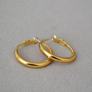 Detailed close-up of high-polish golden hoop earrings with secure lever-back closure