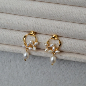 Macro detail of gold flower earrings with small pearls, crystal center and drop pearl
