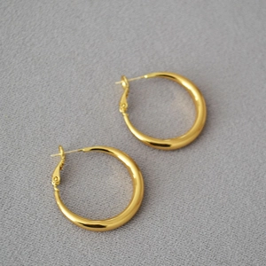 Close-up of polished gold hoop earrings featuring a minimalist round design and secure pin closure