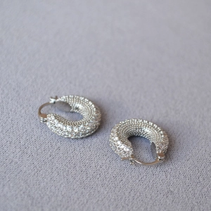 Detailed view of silver pavé hoop earrings with shimmering white cubic zirconia stones