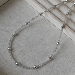 Detailed view of grey beaded necklace with faceted crystals and pearls in a jewelry box