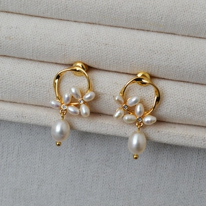 Close-up of gold flower earrings with freshwater pearls and baroque drops on a roll