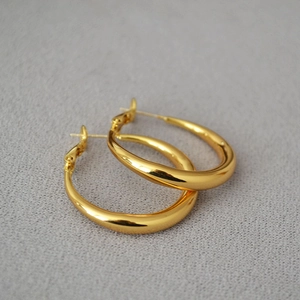 Close-up of polished gold-plated chunky hoop earrings with a smooth metallic finish