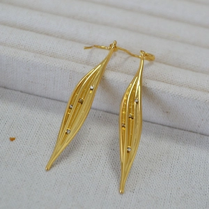 Close-up of golden leaf drop earrings with sparkling zircon crystals and embossed lines
