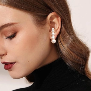 Detail of five graduated white pearls in a crawler earring design on the earlobe