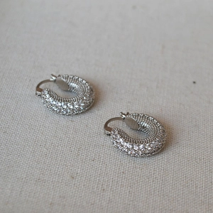 Close-up of silver micro-pave cubic zirconia hoop earrings on linen fabric background