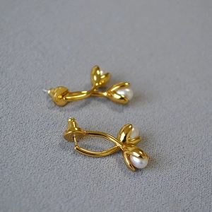 Detailed view of elegant tulip-shaped gold earrings with lustrous drop pearls