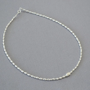 Macro view of minimalist silver beaded necklace with rectangular pendant and oval spacers