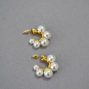 Detailed shot of C-shaped gold-plated brass earrings with elegant white gradient pearls