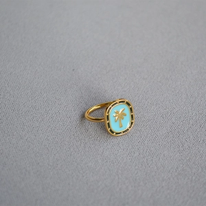 Close-up of gold plated brass signet ring with blue enamel and golden palm tree design