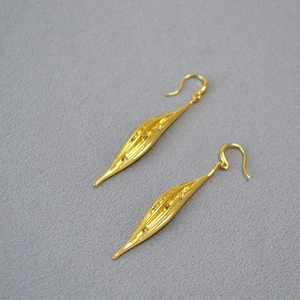 Elegant gold leaf dangle earrings with sparkling zircon stones on a gray background