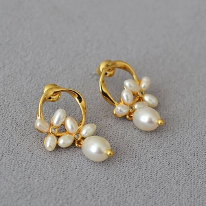 Detail of gold flower earrings featuring freshwater pearls and zircon accents