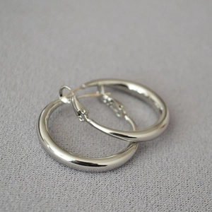 Close-up of chunky silver hoop earrings with a high-polished finish and minimalist design
