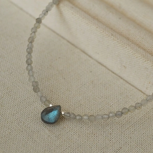 Close-up of teardrop labradorite pendant with blue flash on beaded gemstone necklace