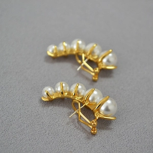 Elegant gold vintage pearl crawler earrings featuring five graduated pearls on a gray surface