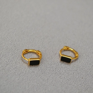 Macro detail of gold plated brass huggie earrings with black enamel rectangular charms