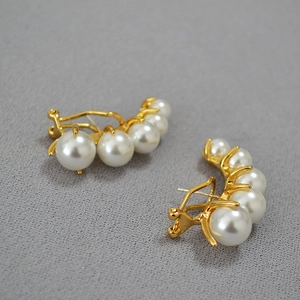 Macro shot of vintage pearl earrings with gold base featuring five graduated pearls