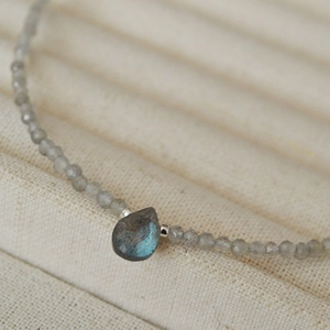 Macro detail of faceted labradorite bead necklace with a teardrop moonstone pendant