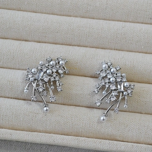 Macro shot of cluster pearl earrings with zircon stones and silver needle details