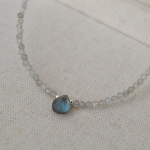 Macro shot of grey faceted stone beads with a blue labradorite teardrop pendant necklace