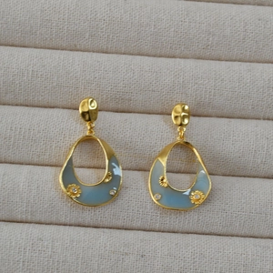 Detail of blue enamel teardrop earrings with gold flower charms and crystals