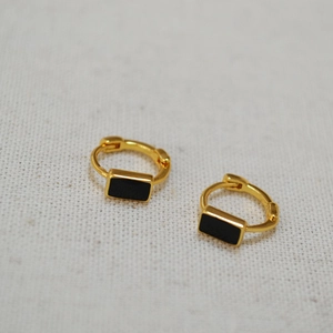 Detail of minimalist gold-plated earrings with rectangular black enamel inlay