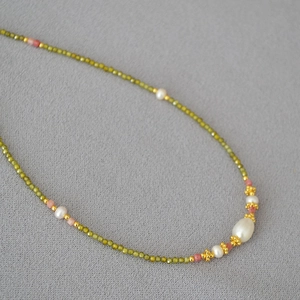 Détail macro du collier en pierres vertes facettées avec perles et perle baroque