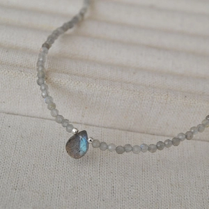 Macro shot of faceted grey labradorite beads with a blue flash teardrop pendant